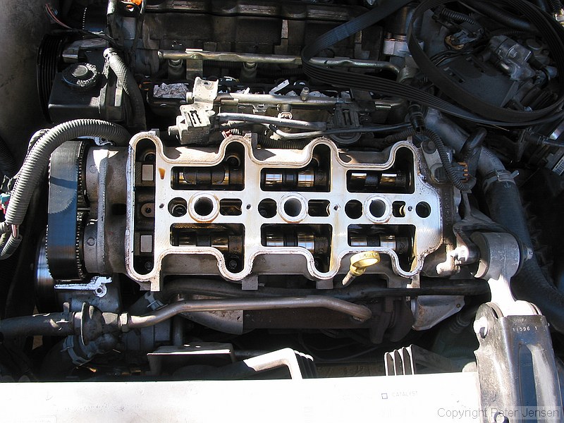 inside of a 1996 Chevrolet Lumina vin X 3.4L engine with the top bits removed while a neighbor changes the timing belt