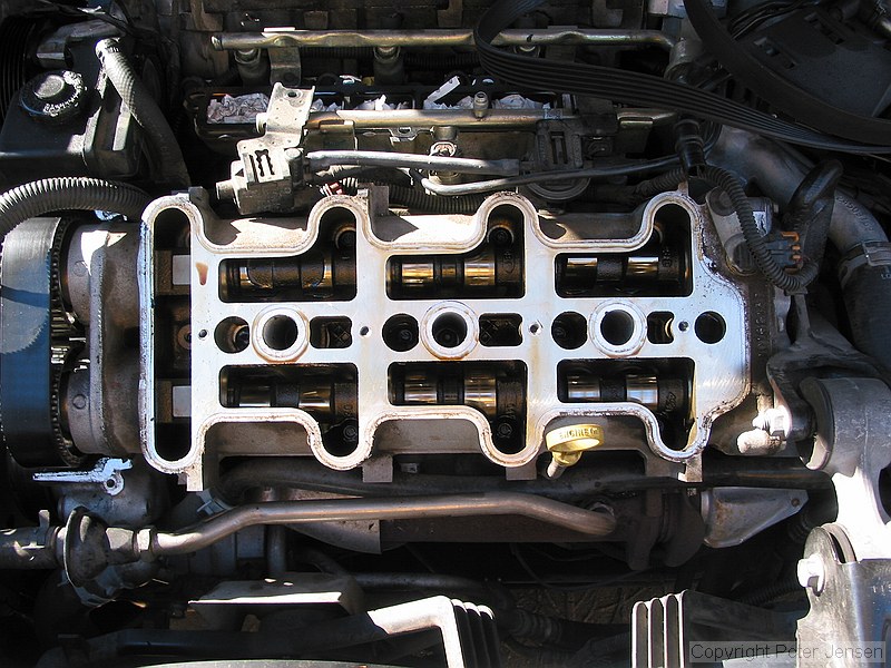 inside of a 1996 Chevrolet Lumina vin X 3.4L engine with the top bits removed while a neighbor changes the timing belt