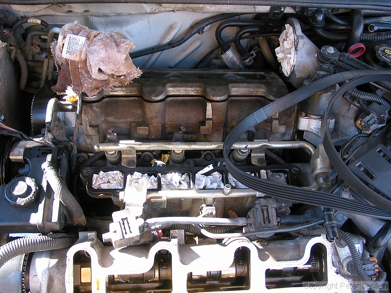 inside of a 1996 Chevrolet Lumina vin X 3.4L engine with the top bits removed while a neighbor changes the timing belt