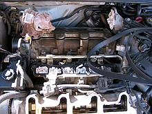 inside of a 1996 Chevrolet Lumina vin X 3.4L engine with the top bits removed while a neighbor changes the timing belt