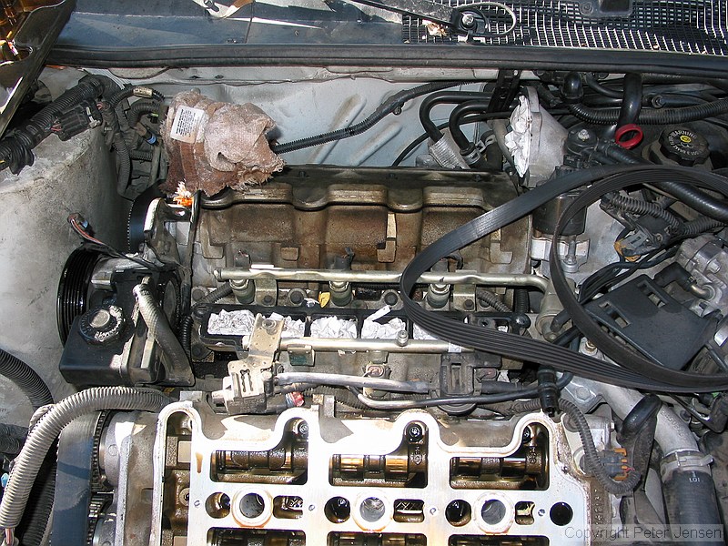 inside of a 1996 Chevrolet Lumina vin X 3.4L engine with the top bits removed while a neighbor changes the timing belt