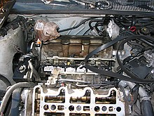 inside of a 1996 Chevrolet Lumina vin X 3.4L engine with the top bits removed while a neighbor changes the timing belt