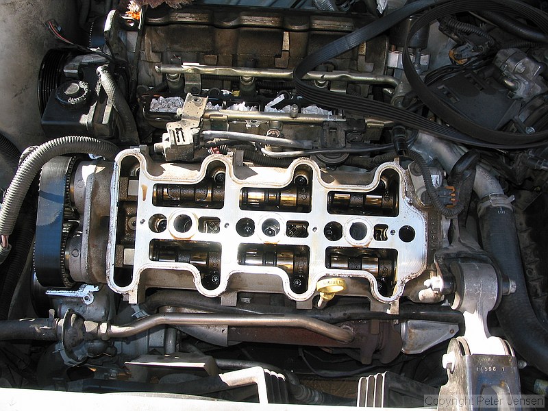inside of a 1996 Chevrolet Lumina vin X 3.4L engine with the top bits removed while a neighbor changes the timing belt