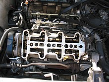inside of a 1996 Chevrolet Lumina vin X 3.4L engine with the top bits removed while a neighbor changes the timing belt