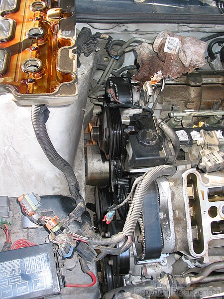 inside of a 1996 Chevrolet Lumina vin X 3.4L engine with the top bits removed while a neighbor changes the timing belt