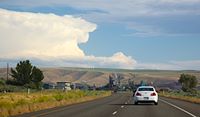 storm brewing over the hills with a wind farm and the polluting Boise paper mill