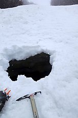 several foot deep hole in the snow down to a drainage - snow bridge failure