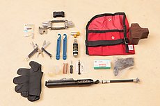 gravel bike kit: two spare 11s links, short and long cleat bolts, multi tool, leatherman squirt ps4, tire levers, CO2, PTAP Designs tool roll, 7mil gloves (first aid/repair), container for bacon, bacon strips, installer, spare valve, patch kit, spare derailleur hangar, pump. Spare tube and sealant not pictured.